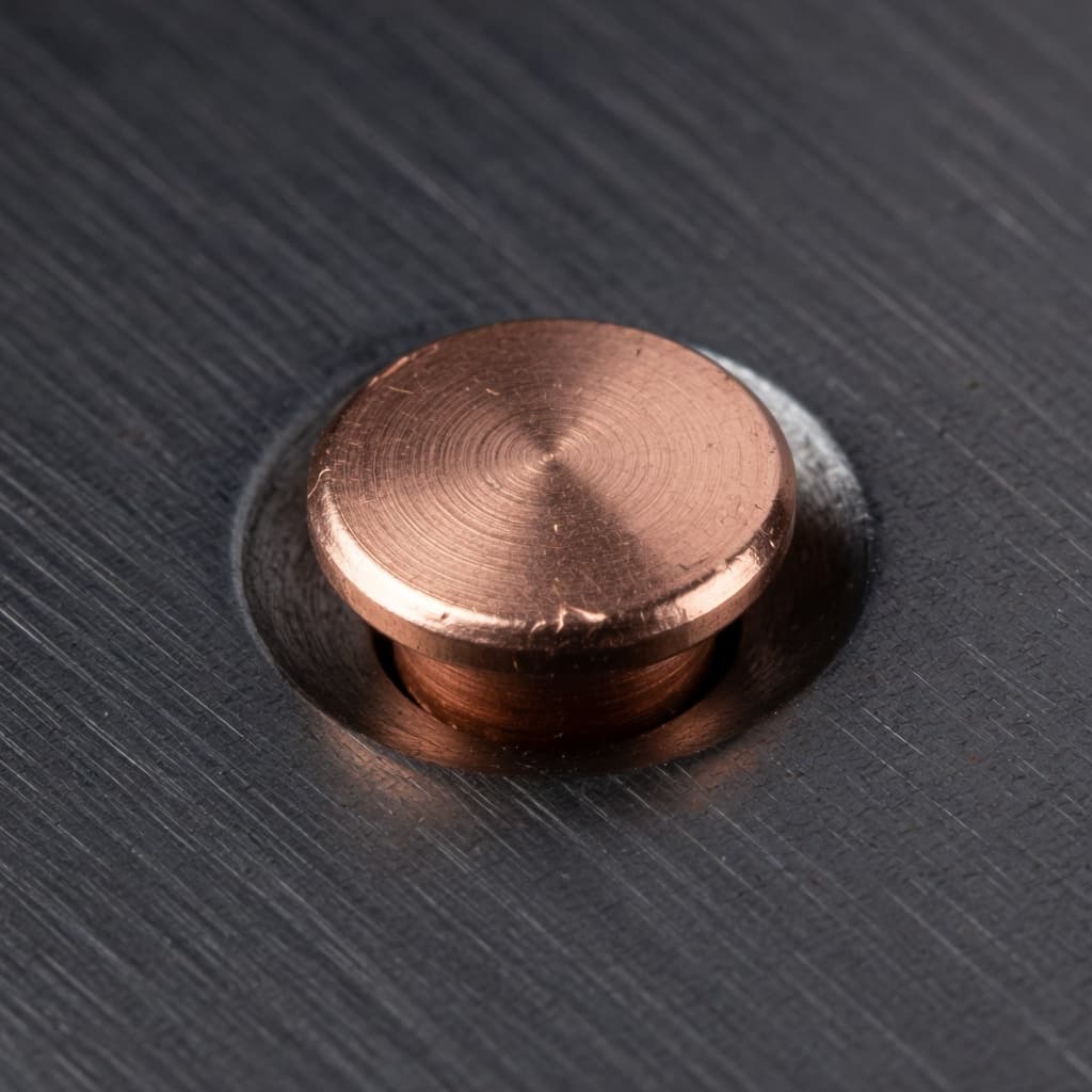 A copper rivet set in brushed steel